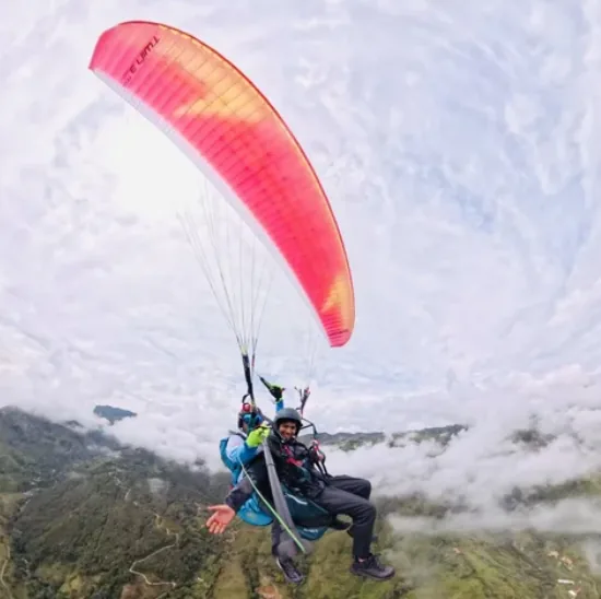Parapente volando por encima de las nubes en el cielo de Antioquia